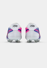 Ποδοσφαιρικά παπούτσια Nike σε λευκό, μπλε και ροζ χρώμα. Διαθέτουν λεία υφή, διαμορφωμένη πίσω σόλα και διακριτικά καρφιά για πρόσφυση. Λογότυπο στη φτέρνα.
