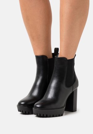 Mustat nahka ankle-bootsit joustavilla sivupaneeleilla, korkea lohkarekorko ja teksturoitu pohja. Varustettu vedä-nauhalla, joka helpottaa pukemista.