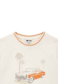 T-shirt crème avec un col orné d'orange, comportant un graphique d'une voiture vintage et d'un ours, avec des palmiers en arrière-plan.