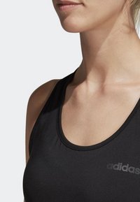 Black athletic tank top with a scoop neckline and racerback design. Features a subtle adidas logo on the left side. Smooth fabric texture.