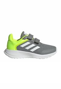 Baskets de sport grises avec des accents blancs et deux sangles Velcro. Présente une tige texturée, un talon vert vif et une semelle blanche rembourrée.
