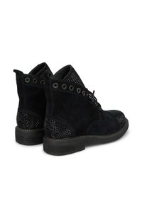 Des bottines en daim noir présentent un panneau tissé texturé, des œillets en métal ronds et une semelle en caoutchouc souple. Conçues avec un devant à lacets.