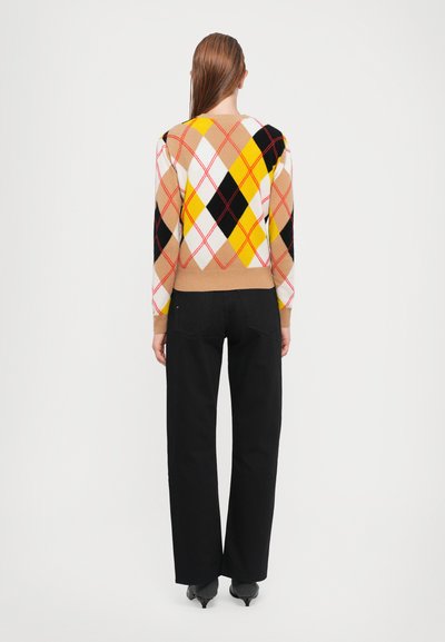 Knit pullover featuring an argyle pattern in beige, yellow, black, and red. The sleeves are patterned, with a fitted hem. Worn with black pants.