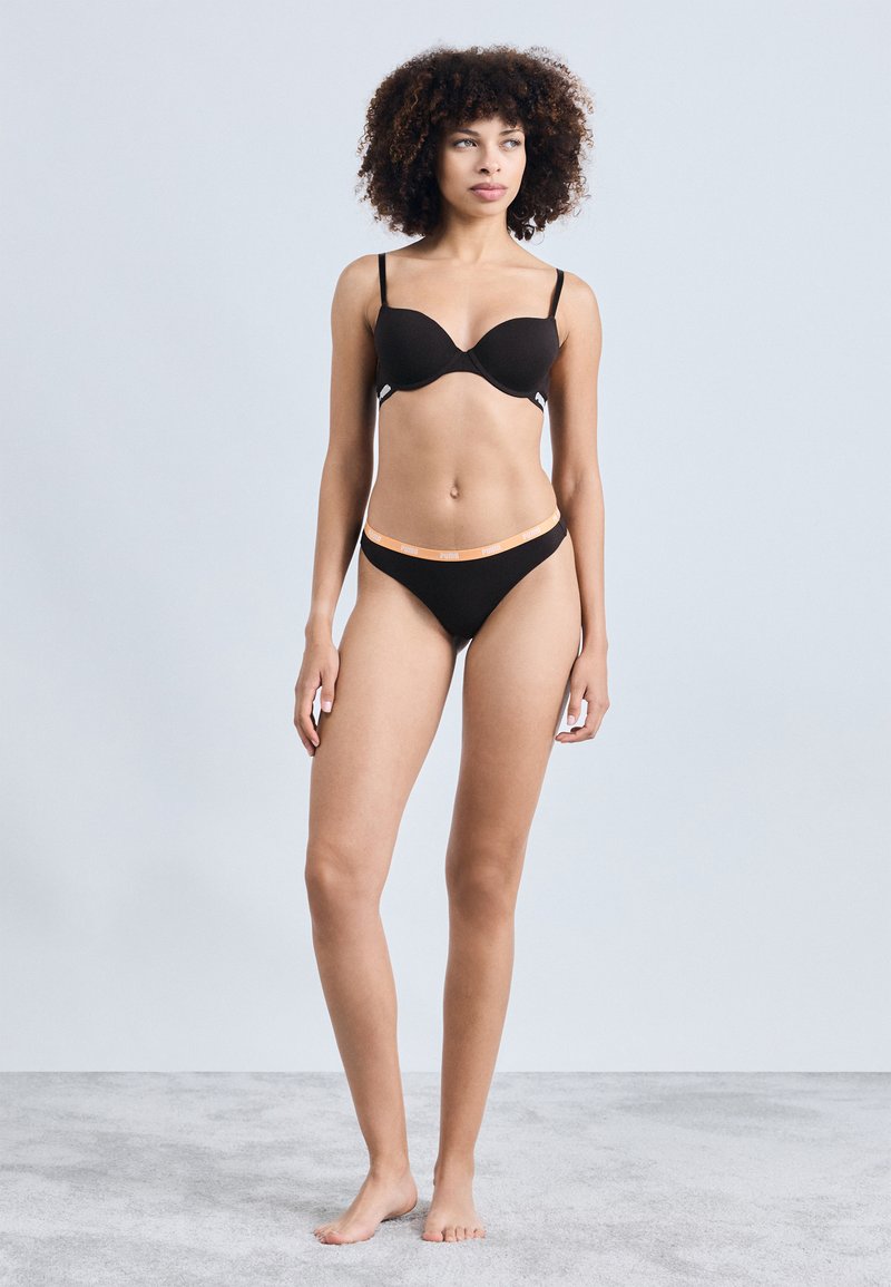 Sutien negru căptușit și chilot asortat cu un tiv portocalie. Material neted și elastic; design minimalist; bretele ajustabile.