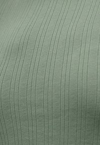 Κοντινή λήψη απαλού πράσινου υφάσματος με ραβδώσεις και κάθετες υφασμάτινες γραμμές.