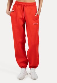 Rode sweatpants met elastische boorden, een bindkoord in de taille en zijzakken. Bevat witte logo geborduurde op de linker dij. Zacht materiaal.