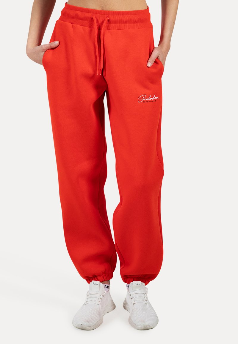 Rode sweatpants met elastische boorden, een bindkoord in de taille en zijzakken. Bevat witte logo geborduurde op de linker dij. Zacht materiaal.