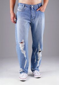 Hellblaue, ausgewaschene Denim-Jeans mit großen Rissen, ausgefransten Kanten und lockerem Schnitt. Verfügt über fünf Taschen und einen Knopfverschluss.