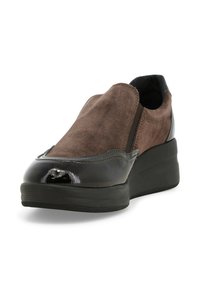 Scarpa slip-on in suede marrone con accenti neri lucidi, punta arrotondata e pannelli laterali elasticizzati, dotata di un tacco spesso per un'altezza maggiore.