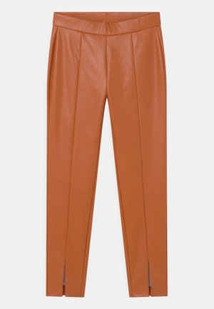 Smeđe faux kožne uske hlače visokog struka s prednjim šavovima i malim prorezima na rubovima gležnjeva, prikazane na bijeloj pozadini.