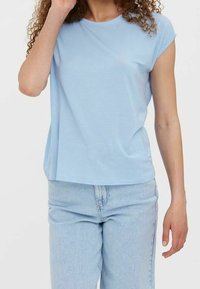 Jasnoniebieski t-shirt z krótkim rękawem z miękkiego materiału o luźnym kroju, połączony z jasnoniebieskimi jeansami. Brak wyraźnych wzorów lub dodatków.