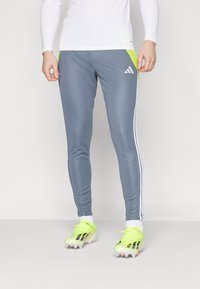 Gray athletic pants with white stripes, made of soft material. Features neon green accents and a slim fit design. Pairing with bright cleats.