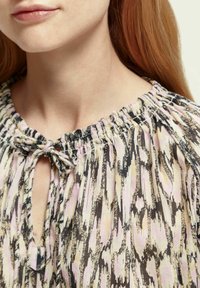 Blusa leggera e stampata con scollatura arricciata e dettaglio a chiave, con tonalità di rosa, marrone e crema. Tessuto morbido.