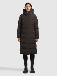 Pikk must sulejope kõrge krae ja kapuutsiga, millel on esilukk, küljetaskud ja tikitud muster. Kandmiseks valitud mustad retuusid ja saapad.