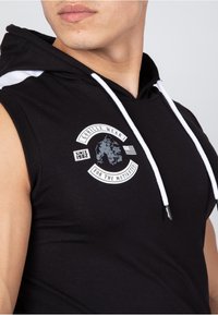 Black sleeveless hoodie with a white drawstring, featuring a graphic logo on the chest and the text "GORILLA WEAR FOR THE MOTIVATED."