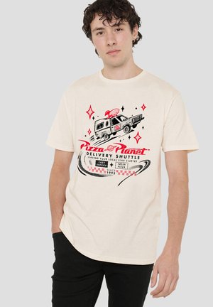 Junger Mann trägt ein cremefarbenes T-Shirt mit einer Grafik eines alten Lieferwagens und dem Schriftzug "Pizza Planet Delivery Shuttle" sowie einem Weltraumthema.