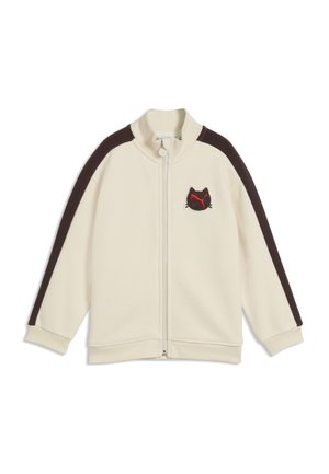 Cremefarbene Zip-Up-Jacke mit schwarzen Streifen an den Ärmeln und einem kleinen schwarzen Katzenkopf-Logo mit rotem Design auf der linken Brust.