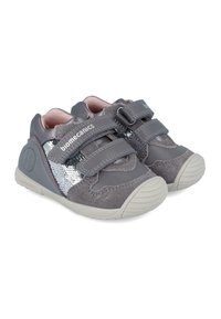 Zapatos infantiles grises con diseño de tira de velcro, material de ante texturizado, detalles plateados brillantes y suela de goma.