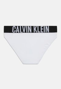 Λευκά εσώρουχα στυλ μπικίνι με μαύρη ελαστική ζώνη μέσης που φέρει μεγάλα λευκά γράμματα "CALVIN KLEIN".