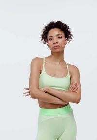 Lichtgroene sportbeha en hooggetailleerde leggings, gemaakt van glad, rekbaar materiaal met brede taillebanden. Eenvoudig ontwerp zonder patronen.