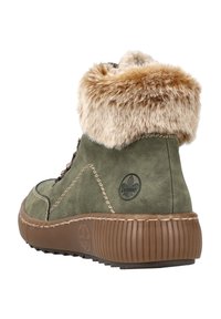 Bottines en daim vert avec col en fausse fourrure, semelle en caoutchouc brun, surpiqûres contrastées et détail de logo sur le côté.