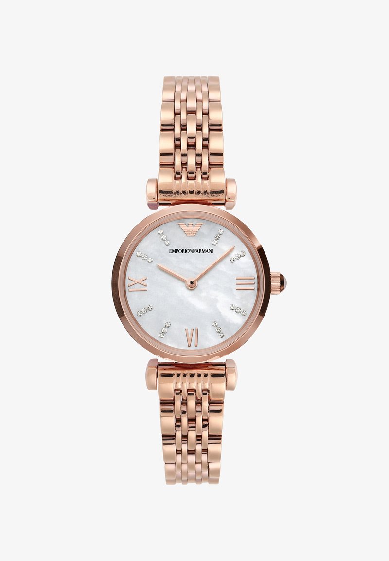 Růžově zlaté hodinky s kulatým pouzdrem, ciferníkem z perleti, římskými číslicemi a krystalovými akcenty. Obsahují spojený kovový náramek.