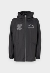 Black, lightweight jacket with a hood, featuring front zipper, two side pockets, and printed text detailing on the chest and sleeve.