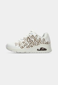 White athletic shoe featuring a textured upper with gold looping patterns, cushioned midsole, and a visible air bubble in the heel.