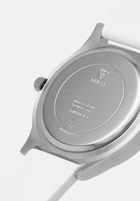 Achterkant van het roestvrijstalen Guess-horloge met witte band, met aanduiding van waterbestendigheid en modelnummer GW0381L1.