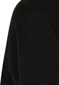 Svart strikket genser med V-hals; har ribbestruktur ved halsen og glatt, finstrikket kropp. Enkel, monokromatisk design.