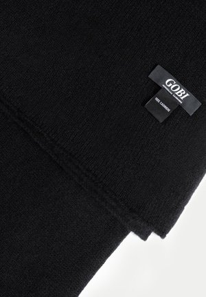Schwarzer mongolischer Kaschmirschal mit gesteppten Kanten und einem Etikett mit der Aufschrift "GOBI 100% Kaschmir" auf weißem Hintergrund.