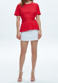 Rød bomuld t-shirt med en tætsiddende talje og korte ærmer, kombineret med en hvid denim mini-skirt med flosset kant.