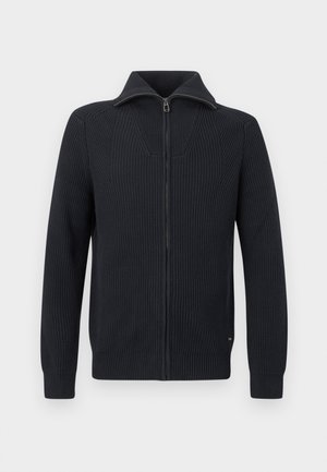 Melns adīts džemperis ar rāvējslēdzēju, garām piedurknēm, ribota faktūra un stāvus apkakli, attēlots uz balta fona.