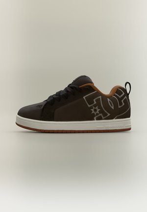Baskets basses marron foncé avec lacets noirs, doublure intérieure orange, semelle blanche et grand logo stylisé sur le côté.