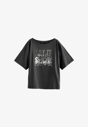 Camiseta corta negra de manga corta con un escote amplio y un gráfico decorado con lentejuelas que dice "QUE NIEVE" en plata y blanco.