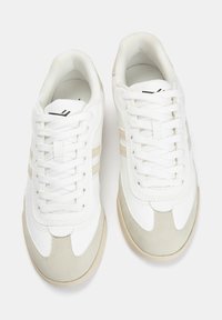 Sneakers bianchi con accenti beige, caratterizzati da una tomaia in pelle liscia, fodera in rete testurizzata e chiusura tradizionale con lacci. Suola in gomma.
