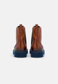Bottines en cuir marron avec des panneaux élastiques sur les côtés, semelle en caoutchouc bleue, détails brogue et languette à l'arrière. Design minimaliste.
