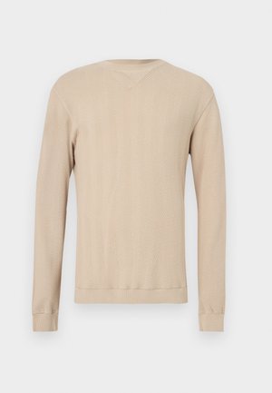 Pull beige à manches longues avec un motif en chevrons, doté d'un col en V, de poignets côtelés et d'un design en tricot texturé. Tissu doux.