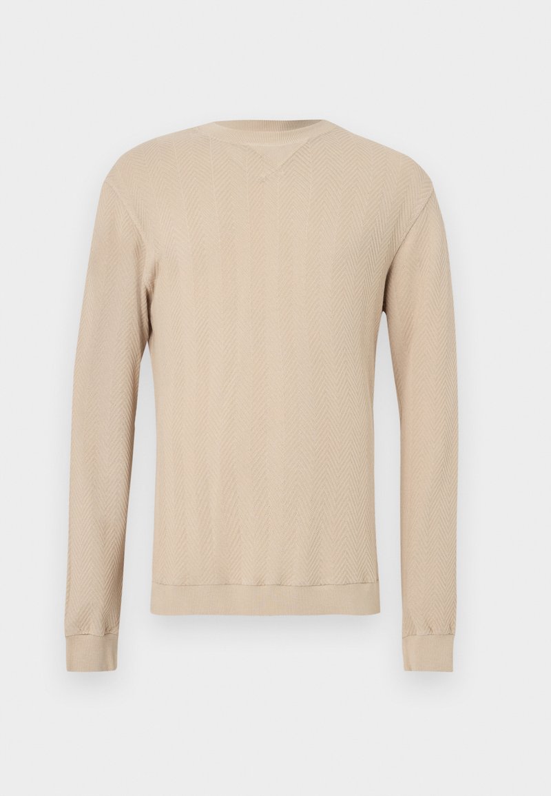 Pull beige à manches longues avec un motif en chevrons, doté d'un col en V, de poignets côtelés et d'un design en tricot texturé. Tissu doux.
