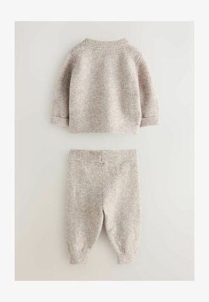 Dwuczęściowy komplet składający się z beżowego swetra dzianinowego z długimi rękawami oraz dopasowanych spodni typu tapered, obie części z prążkowanymi mankietami.