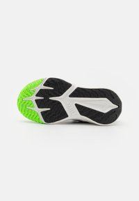 Nike athletic shoe sole featuring a black and white design with bright green accents, textured rubber for traction, and a distinct pattern.
