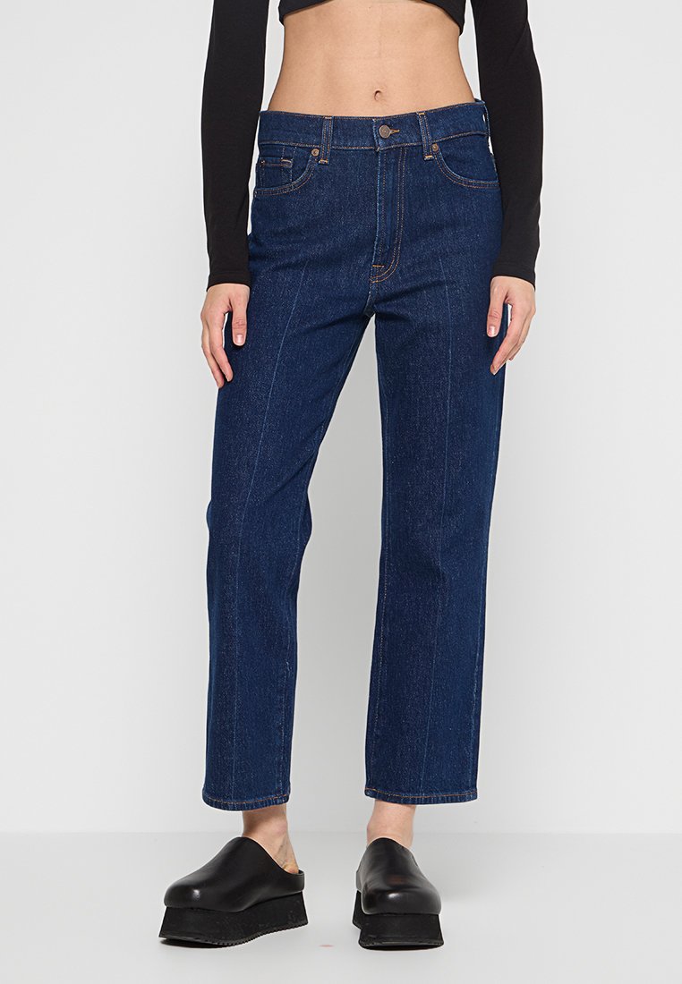 Jeans en denim bleu taille haute avec une coupe droite, dotés de cinq poches, de pièces en cuivre et de détails de surpiqûres visibles.