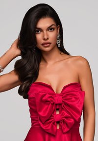 Abito in satin rosso con design senza spalline, caratterizzato da grandi fiocchi sul petto e dettagli con tagli. Tessuto liscio con una silhouette aderente.