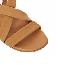 Sandale en daim marron avec des brides entrecroisées, un bout rond et une semelle plate avec une finition lisse.