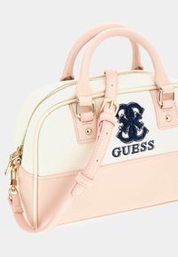 Rechteckige Handtasche mit einem weichen, rosa Kunstlederboden und -griffen, einem cremefarbenen, strukturierten Stoffkörper, gesticktem marineblauem Logo und goldfarbenen Beschlägen.