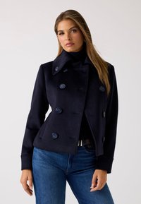 Abrigo de marina de doble botonadura, con amplio cuello y bolsillos laterales. Hecho de una mezcla de lana con una textura suave.