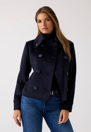 Cappotto marinaro con chiusura a doppio petto, ampio colletto e tasche a lato. Realizzato in tessuto misto lana con una texture liscia.