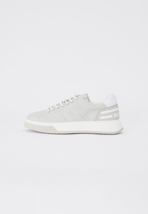 Sneaker bassa grigio chiaro con suola bianca, lacci e toppa sul tallone, con un logo in rilievo sottile sul lato e dettagli a righe sul tallone.