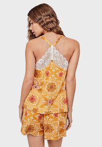 Yellow floral pajama set featuring a lace-trimmed spaghetti strap top and matching shorts with a patterned design and scalloped hem.