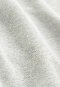 Tessuto grigio chiaro con una consistenza morbida e liscia, caratterizzato da un sottile motivo melange e una caduta leggermente curvata e informale.